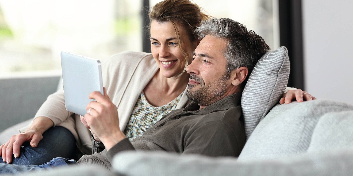 Paar auf der Couch mit ipad, Tablet, Haussteuerung
